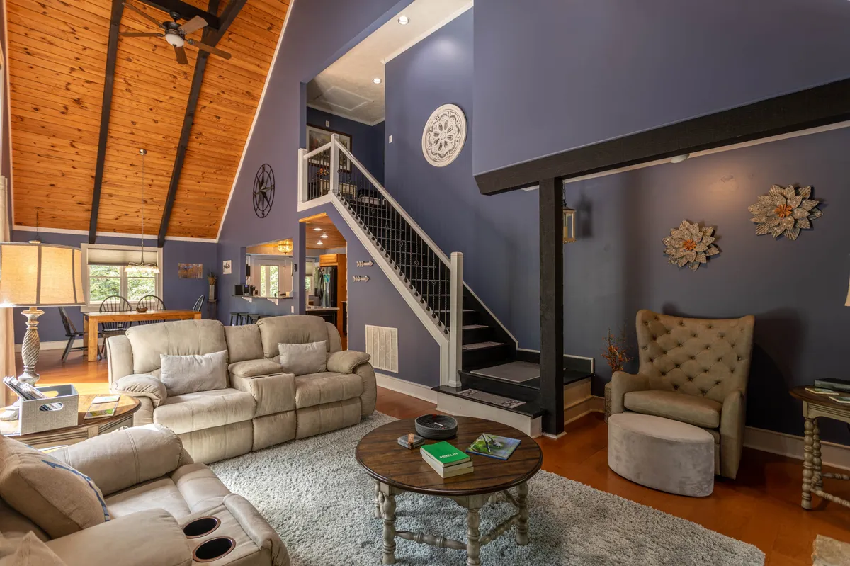 A comfortable seating area with a sofa, coffee table, staircase, and decorative wall accents. The space is designed for both relaxation and casual gatherings, with a welcoming mood and flexible layout suitable for work or family time.
