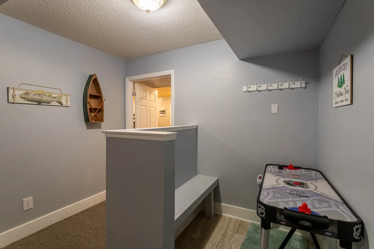 A cheerful indoor recreation area with a full-size air hockey table, distinctive wooden boat decor, and wall hooks for outerwear. The area is well-lit, bright, and designed to encourage friendly competition and group play.