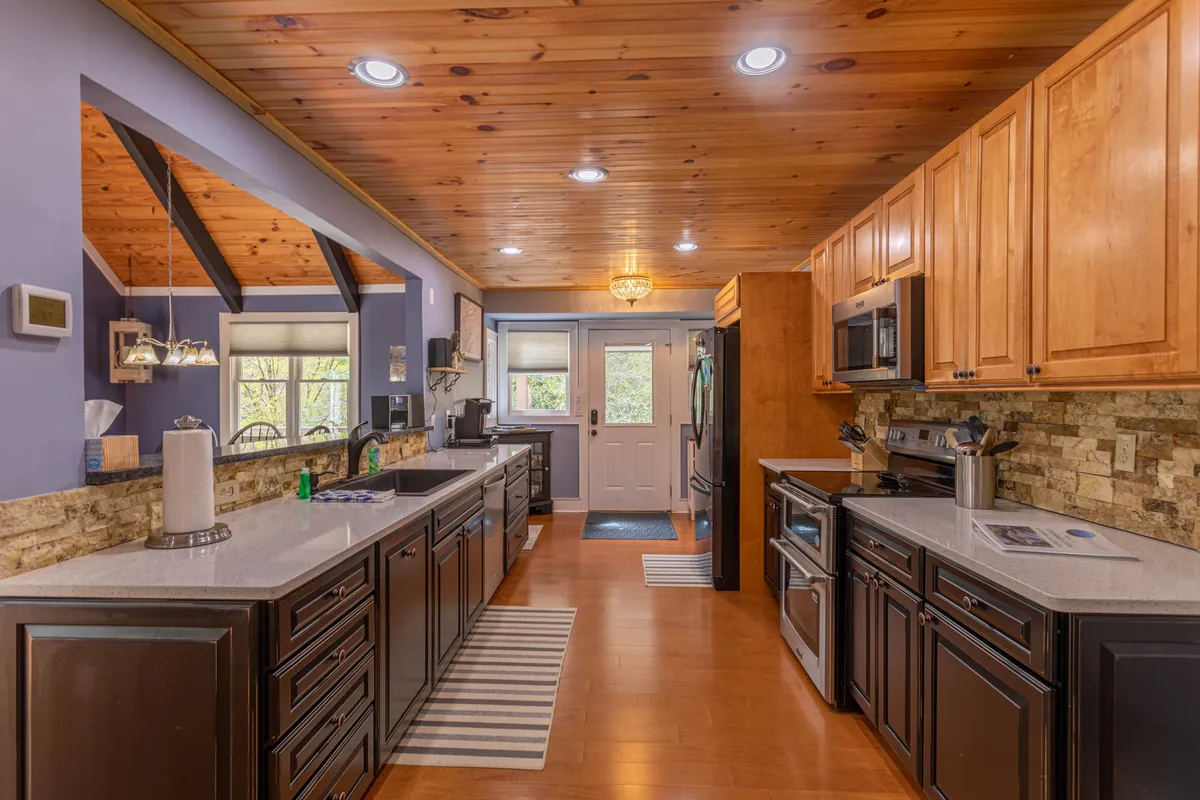Bright kitchen space featuring an island countertop, sleek cabinetry, ample appliances, and windows that invite daylight. The layout is conducive to cooking, casual dining, and socializing, reinforcing the kitchen's role as a hub for culinary creativity and connection.