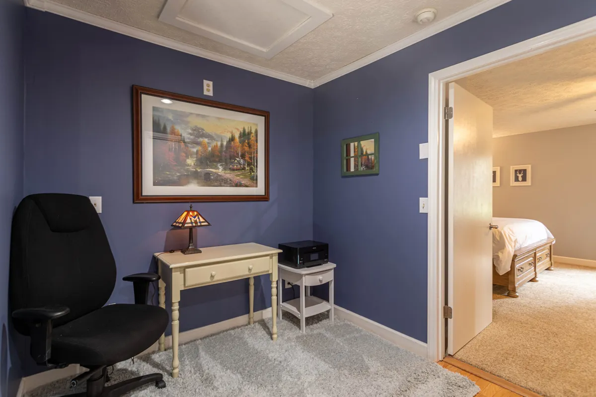 A cozy workspace in the master suite, featuring a desk with a lamp, a comfortable office chair, and inspiring wall art. The area is designed for quiet productivity or reading.