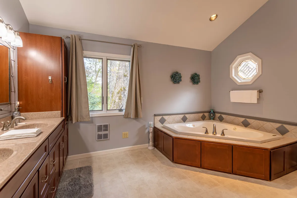 A serene bathroom with a standalone bathtub positioned near a large window, a sleek vanity, and soft natural light illuminating the space. The setup invites guests to enjoy a luxurious soak while taking in peaceful views.