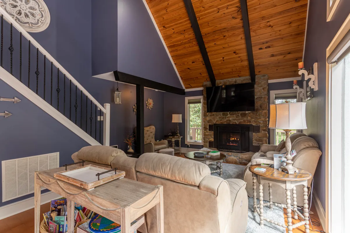 A welcoming interior space featuring a fireplace, comfortable sofa, and a staircase, suggesting a cozy spot for relaxing or gathering. The room is bathed in warm light, with tasteful decor and an inviting atmosphere ideal for unwinding or low-key productivity.