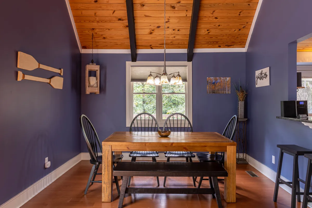 A warm, inviting dining area featuring a wooden table, black chairs, a pendant light fixture, and a window with view to the outdoors. The setting is ideal for shared meals, casual conversations, and creating family memories.